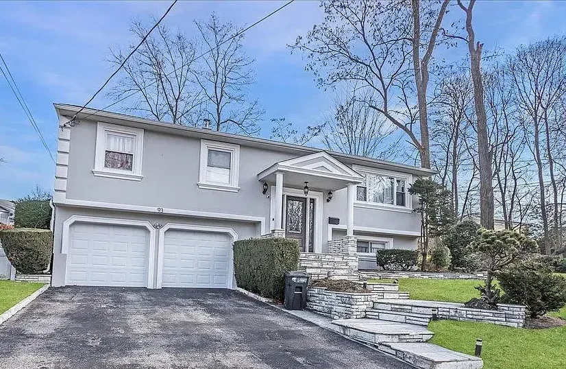 Two-story split-level home with a dark asphalt shingle roof, light exterior siding, attached garage, and clean residential roofing design.